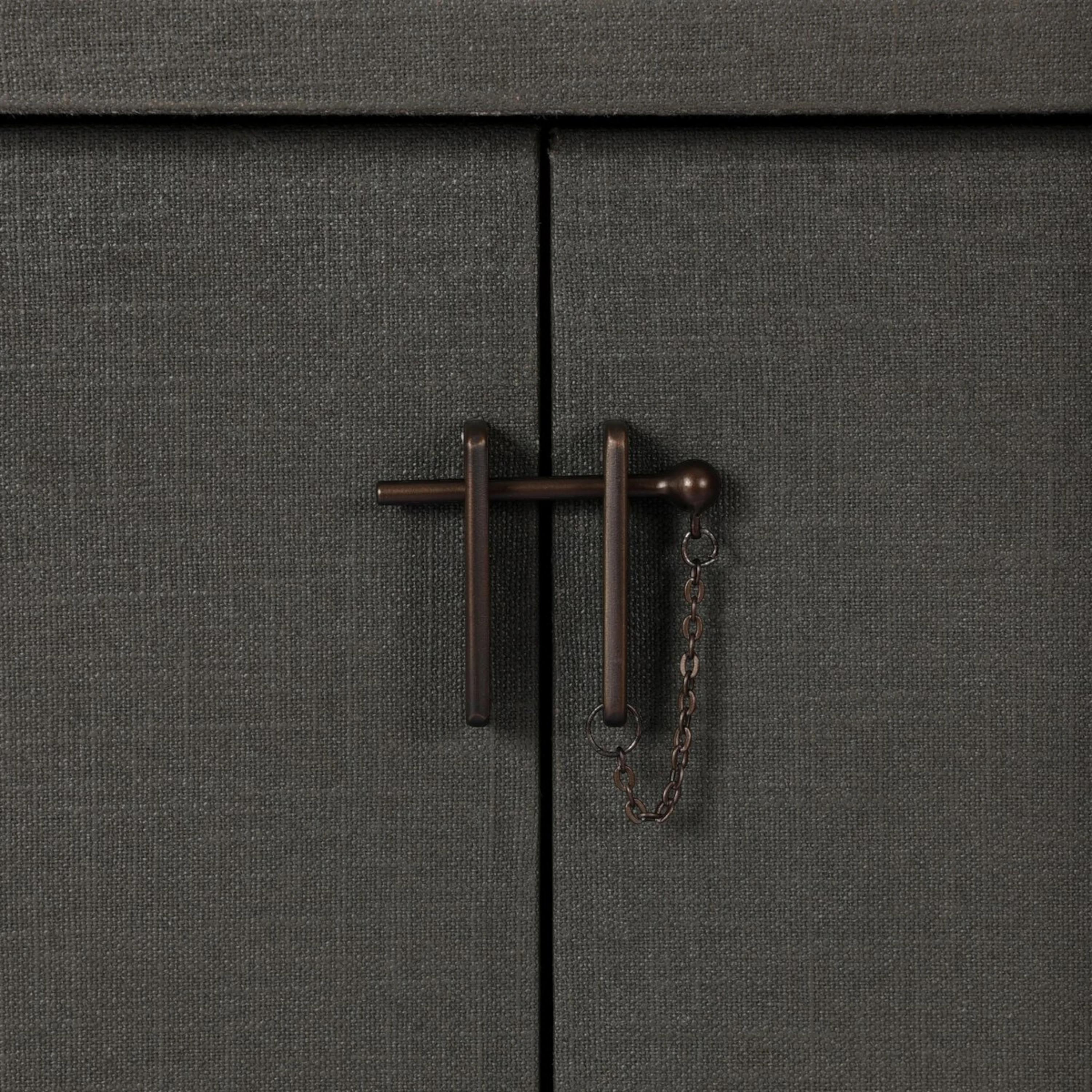 Detail of the Fletcher Sideboard bronze T-bar latch with decorative chain against the textured moss green lacquered linen doors.