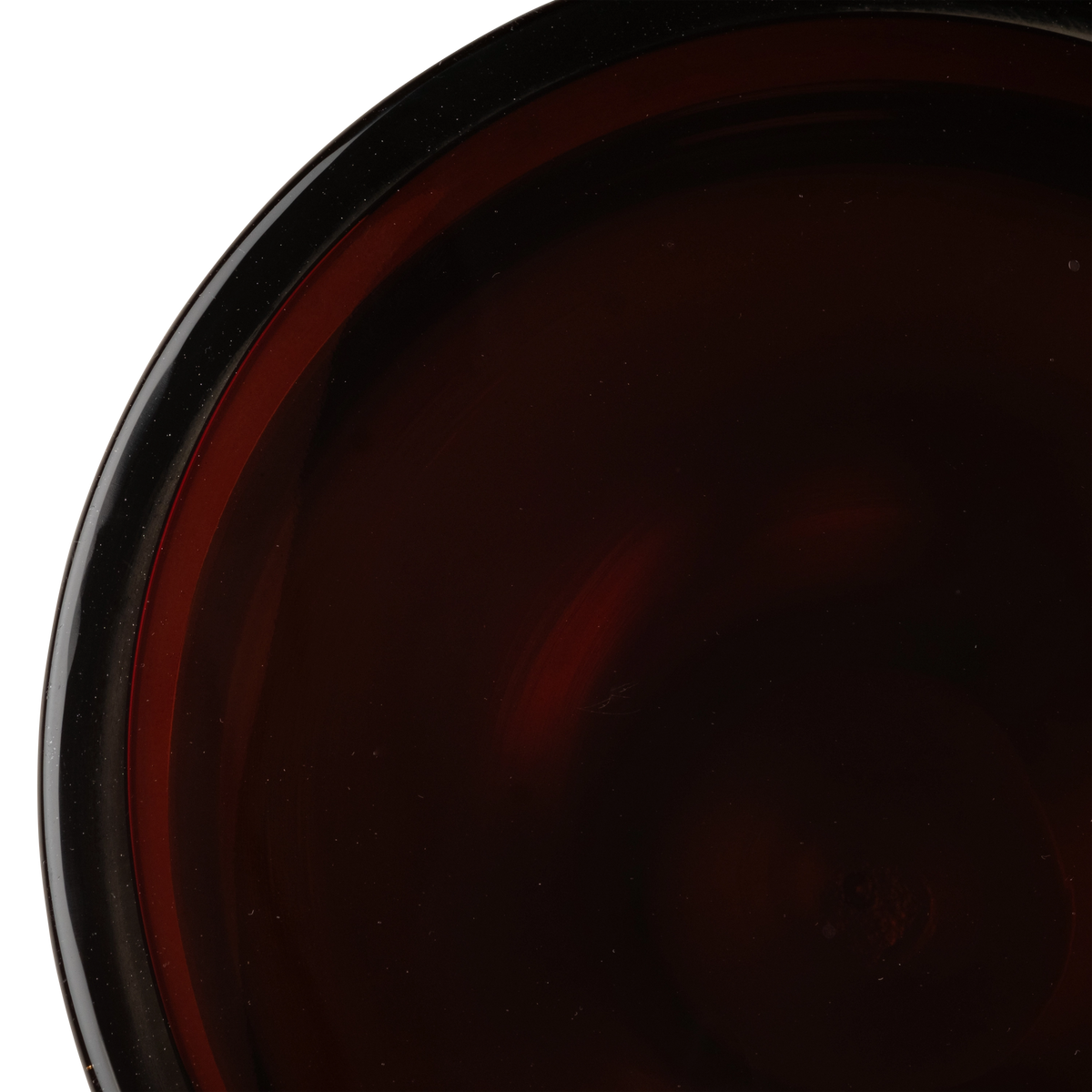 Close-up of the Caden Pull Up Table’s brown glass top, showing deep red swirls, a polished rim, and fine specks within the surface.