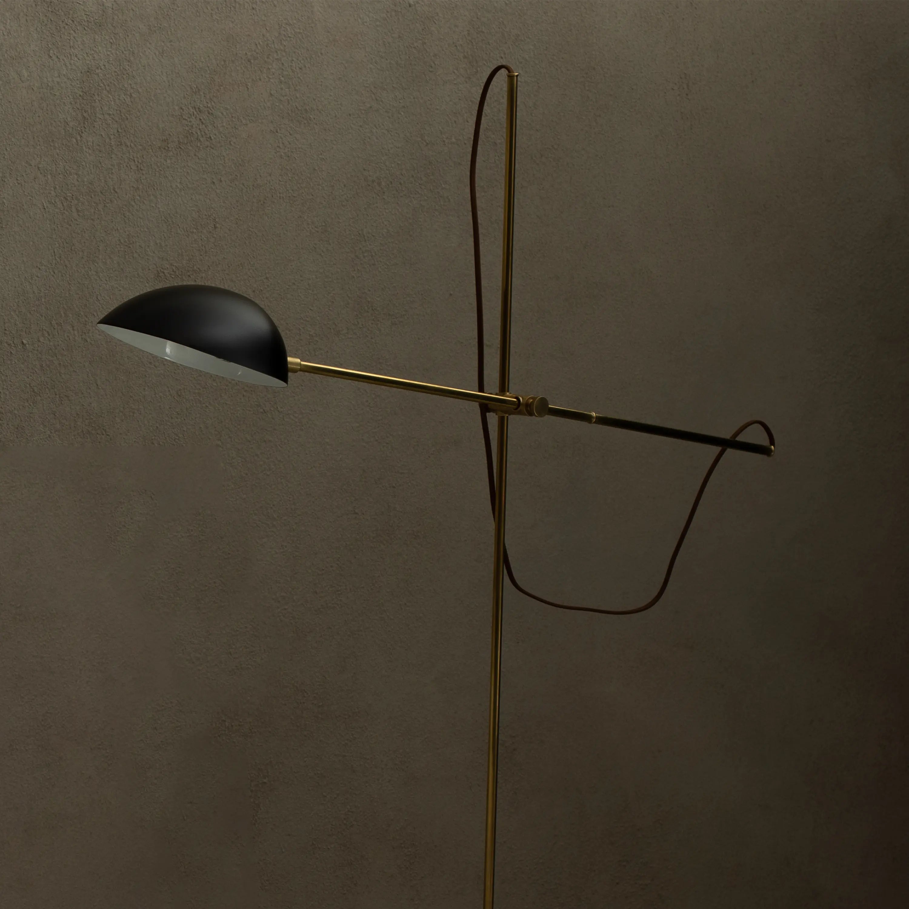 A minimalist floor lamp with an adjustable arm and exposed wire for a contemporary feel.