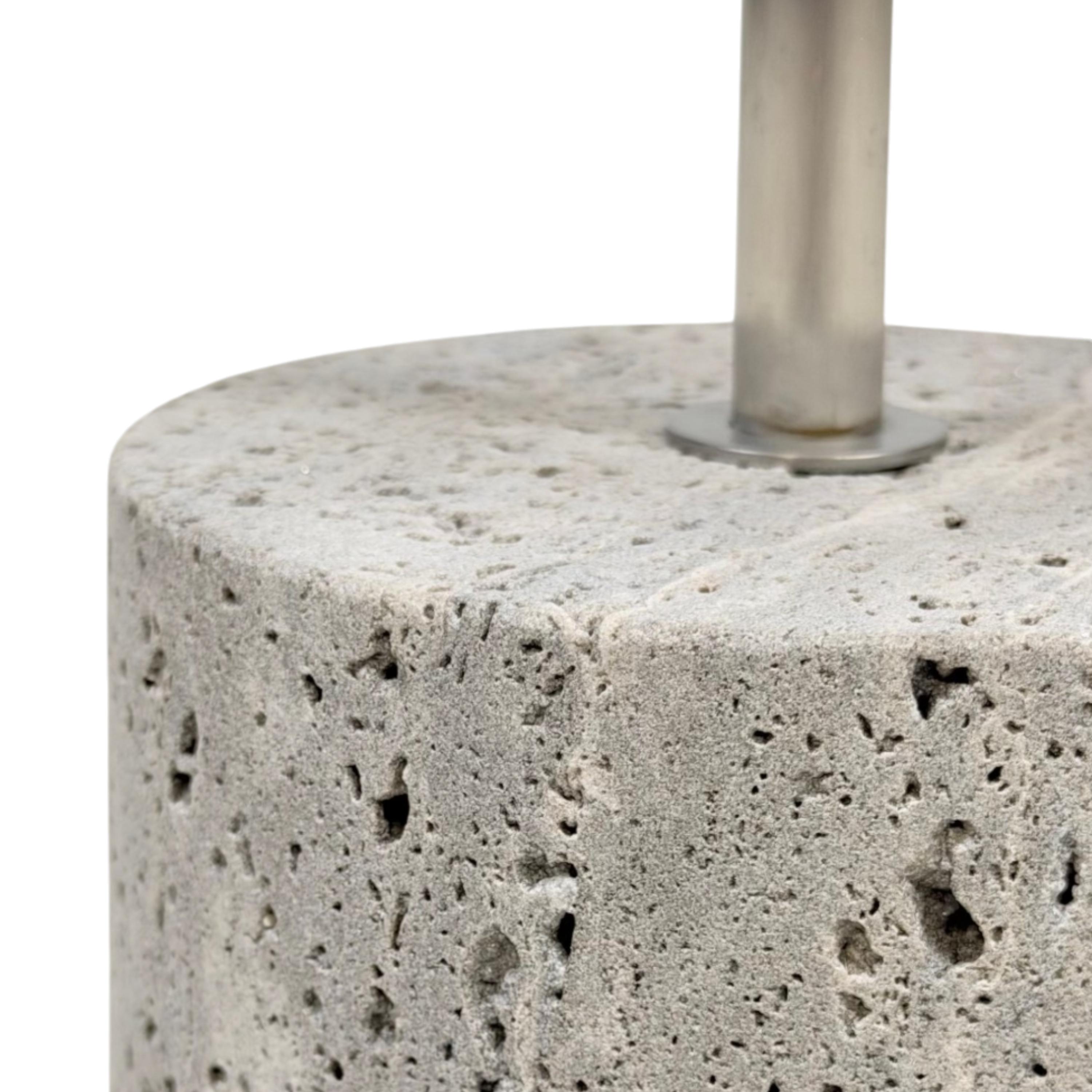 Close-up of the Jasper side table’s cylindrical stone base, showing its porous surface, rounded edge and brushed-metal stem connection