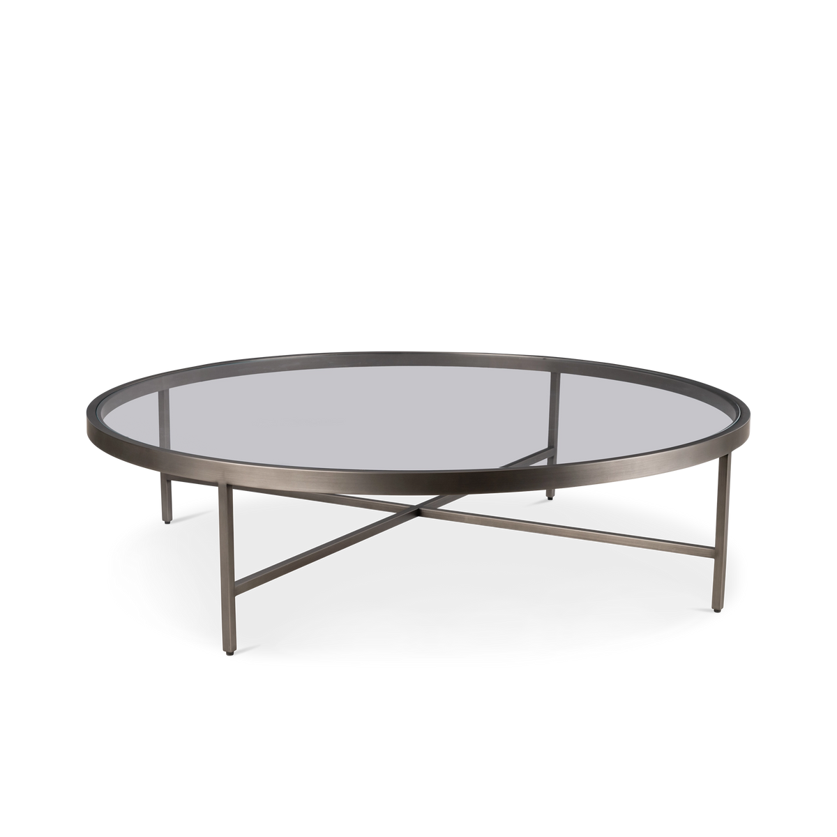 Tenor Round Coffee Table in an angled view in Aged Pewter brushed metal with a round glass top, slim ring frame, four slender legs and a crossed base.