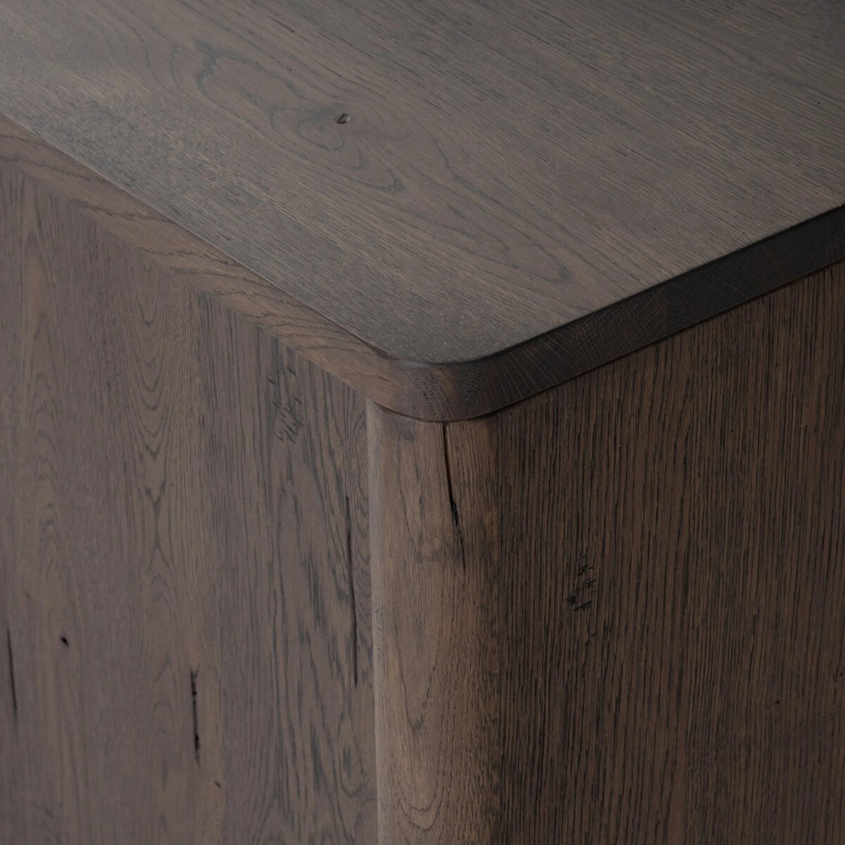 Close-up of the Hewitt Sideboard corner showing the softly rounded edge, dark weathered oak finish and visible natural grain variation.