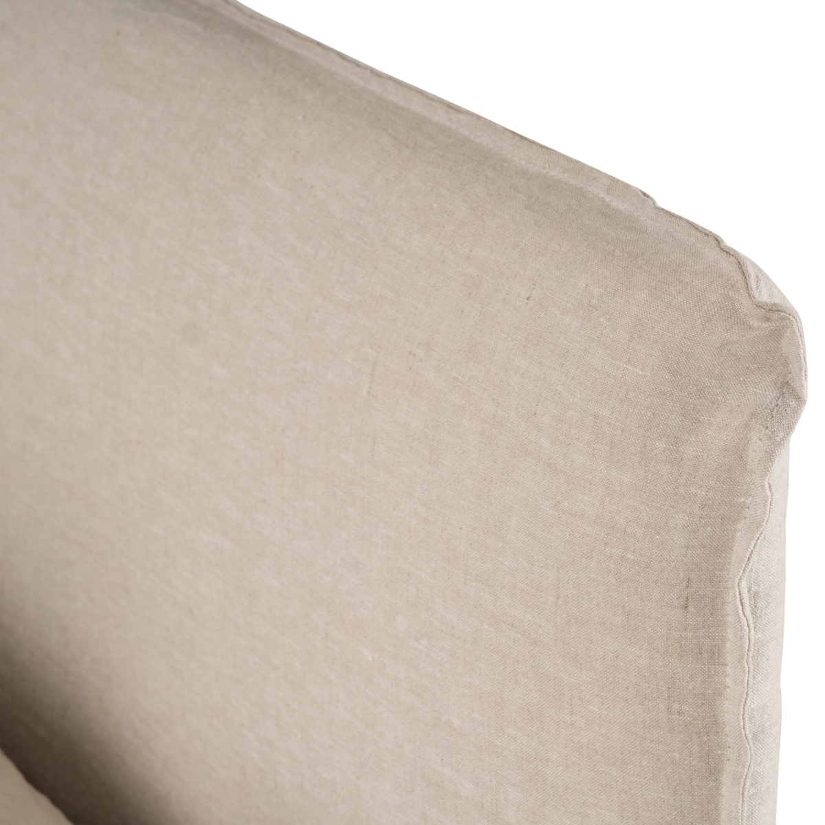 Close-up of the Muse Queen Bed's natural linen headboard, showing the relaxed slipcover, raw-edge seam and softly rounded corner.