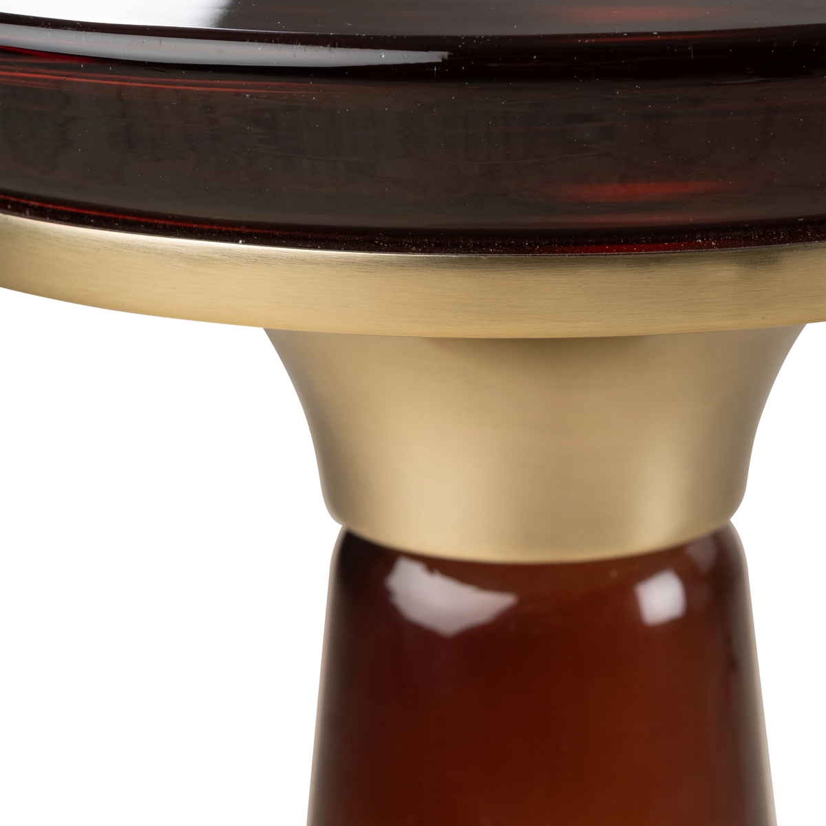 Close-up showing the brushed brass collar where the Caden Pull Up Table’s brown glass pedestal meets the top, with glossy highlights on the curved glass.