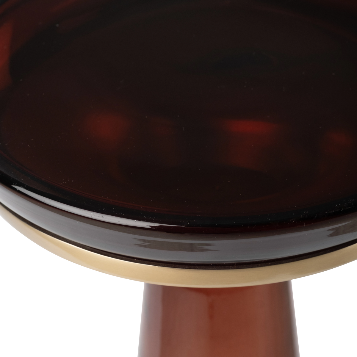 Close-up showing the glossy dark top of the Caden Pull Up Table in brown glass and brass, with the brushed metal collar and the tapered glass stem below.