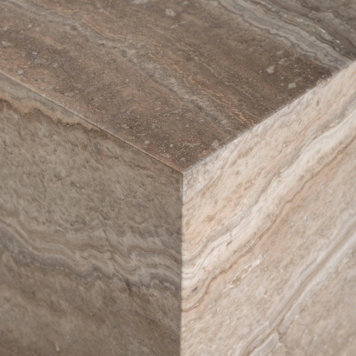 Close-up of the corner of the Duvall Console Table in Taupe travertine, showing the greyer honed top meeting the lighter, sand-toned side with layered veining.