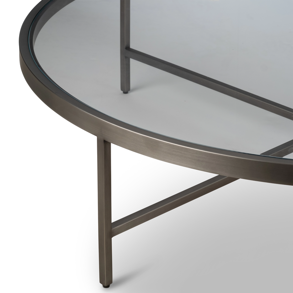 Close-up showing the Tenor Round Coffee Table’s Aged Pewter brushed metal ring, square leg and cross brace joint, with a small foot cap at the base.