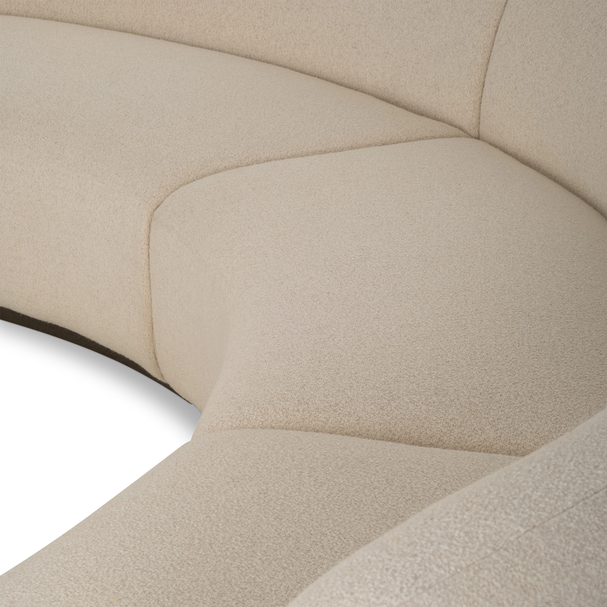 Close-up showing the rounded arm of the Rhine Modular Sectional Sofa in cream bouclé, with the stitched seam along its edge and the curved seat sections beyond it.